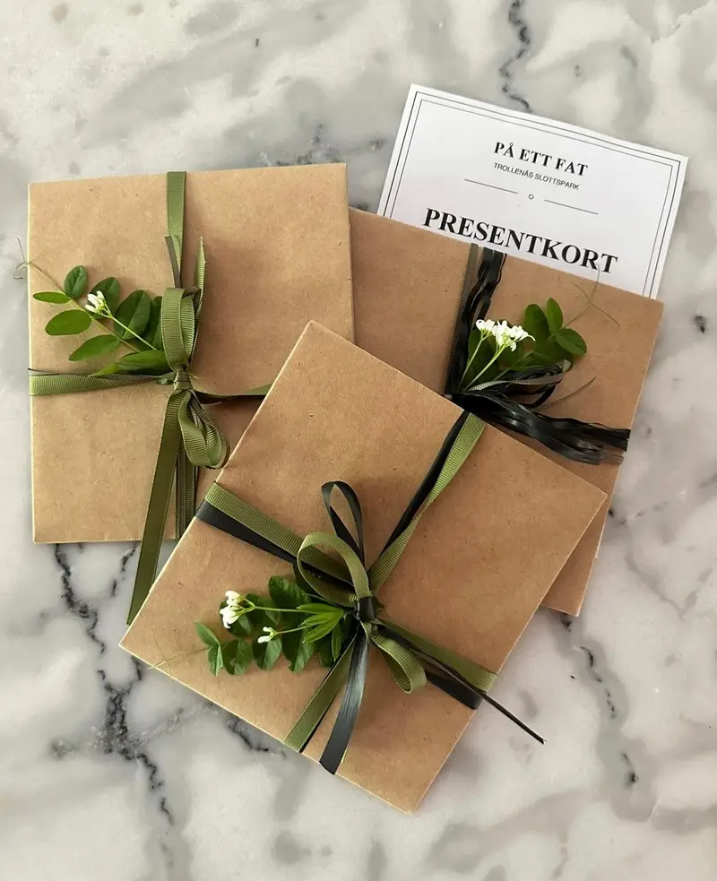 Presentkort från På ett fat, inslagna i bruna paket med grönt band